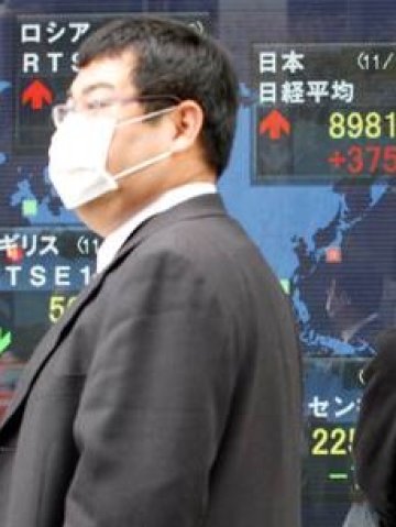 <p>Мъж пред електронно табло в Токио, показващо измененията на индексите по целия свят. <i>Снимка: Ройтерс</i></p>