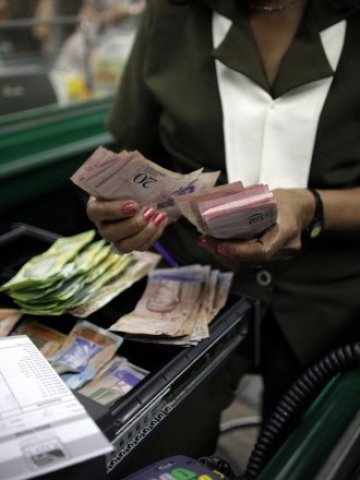 <p>
	Касиерка брои боливари в супермаркет във венецуелската столица Каракас. <em>Снимка: Архив Ройтерс</em></p>
