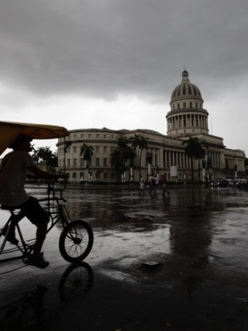 <p>
	Такси-рикша преминава пред сградата на президентския дворец в Хавана.<em> Снимка: Ройтерс</em></p>
