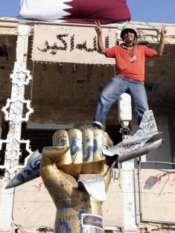 <p style="margin-bottom: 0cm">
	Бунтовник пред резиденцията на Кадафи в комплекса Баб ал-Азизия в Триполи. <em>Снимка: Ройтерс</em></p>
