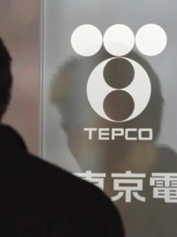 <p>Отражението на мъж на входната врата на централата на Tepco в Токио. <i>Снимка: Ройтерс</i></p>