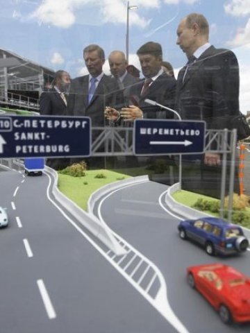 <p>
	Путин (вдясно) и държавни служители разглеждат изложение за пътно строителство в Твер. <em>Снимка: Ройтерс</em></p>
