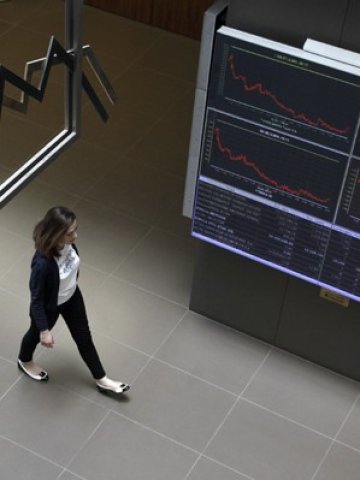 <p>
	Жена минава край електронни табла с котировки на фондовата борса в Атина. <em>Снимка: Ройтерс</em></p>
