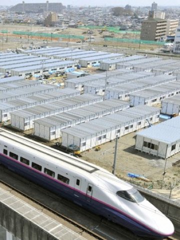 <p>
	Влак-стрела минава покрай временни жилища за оцелелите от природните бедствия. <em>Снимка: Ройтерс</em></p>
