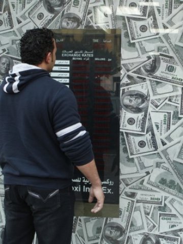 <p>
	Мъж чака реда си пред обменно бюро в Кайро. <em>Снимка: Ройтерс</em></p>
