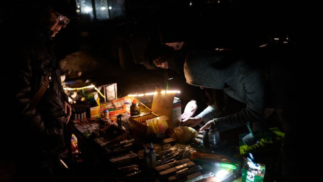 Украинци разглеждат с фенерче стоки на спонтанно появила се сергия по време на прекъсване на тока в Киев. Снимка: Zinchenko/Global Images Ukraine via Getty Images