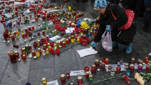 <p>
	Жена пали свещ в памет на жертвите в Мариупол. <em>Снимка: Ройтерс</em></p>
