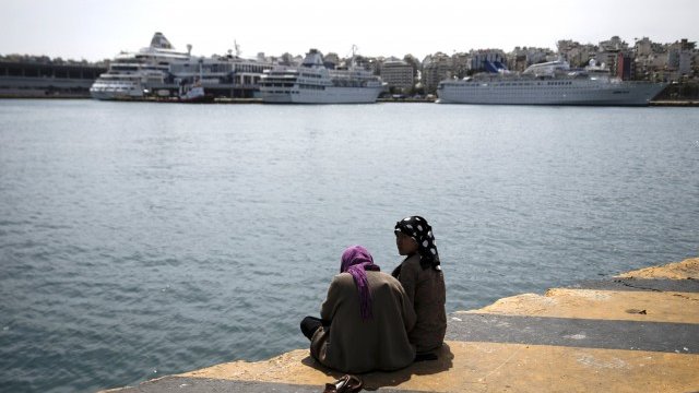 <p>
	Две жени от Афганистан седят на дока до временен лагер за бенанци и мигранти до пристанището на Пирея, в близост до Атина. <em>Снимка: Ройтерс</em></p>
