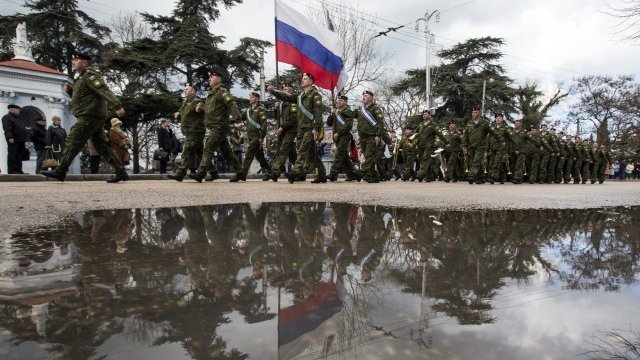 <p>
	Една година след окупацията на Крим руски войски открито маршируват на полуострова, а само преди една година те бяха &quot;местна самоотбрана&quot;. <em>Снимка: Ройтерс</em></p>
