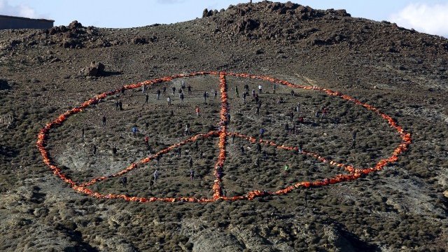 <p>
	Доброволци подреждат във формата на знака на мира над 2500 спасителни жилетки, изоставени от бежанци и мигранти по бреговете на остров Лесбос. <em>Снимка: архив Ройтерс</em></p>

