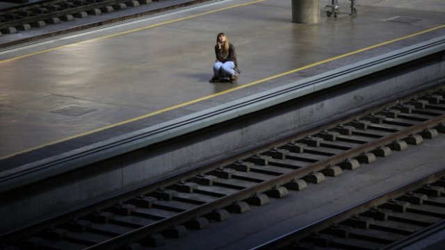 <p>
	Самотна жена чака влака си на гарата в Севиля, Испания. <em>Снимка: Ройтерс</em></p>
