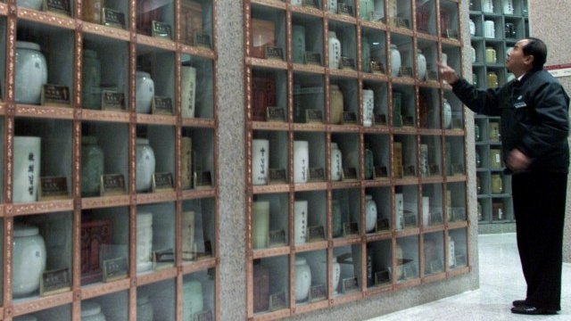 <p>
	Служител оглежда урни в костница в Сеул. <em>Снимка: Ройтерс</em></p>
