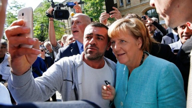 <p>
	<em>Бежанец се снима с Ангела Меркел. Снимка: Ройтерс</em></p>
