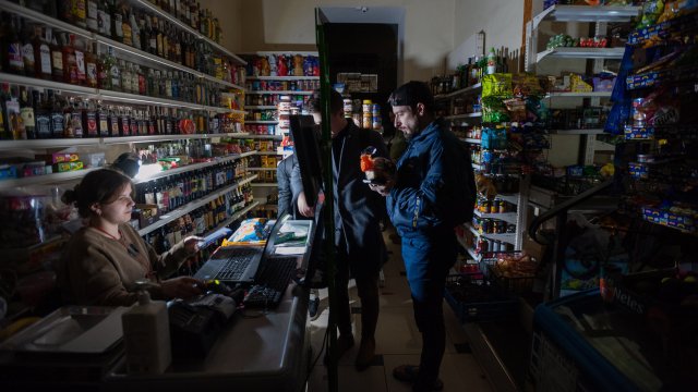 Клиенти пазаруват в магазин в Лвов по време на спиране на електричеството. Снимка:  EPA/MYKOLA TYS