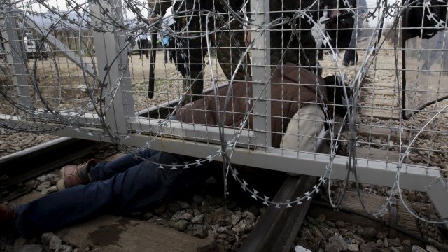 <p>
	Бежанец от Афганистан преминава под загражденията на границата, след като Македония затвори пункта. <em>Снимка: Ройтерс</em></p>
