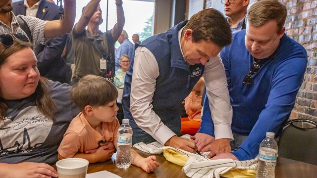 Кандидатът за президент на САЩ Рон ДеСантис подписва бейзболна тениска по време на кампания във Форт Додж, Айова.