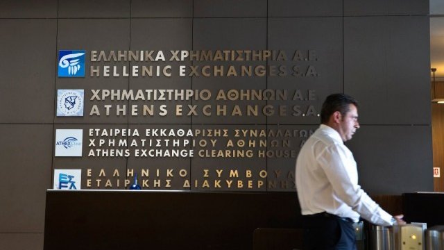 <p>
	Служител по охраната на входа на сградата на фондовата борса в Атина.<em> Снимка: Ройтерс</em></p>
