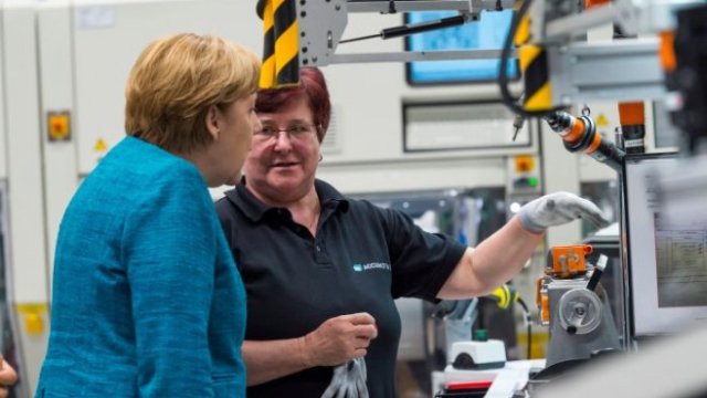 <p>
	Канцлерът на Германия Ангела Меркел разговаря с работничка в първата фабрика за батерии на Daimler. <em>Снимка: Ройтерс</em></p>
