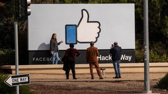 Посетители на централата на Facebook в Мелно Парк, Калифорния, разглеждат един от символите на социалната платформа, изобразен върху билборд. Снимка: David Paul Morris/Bloomberg