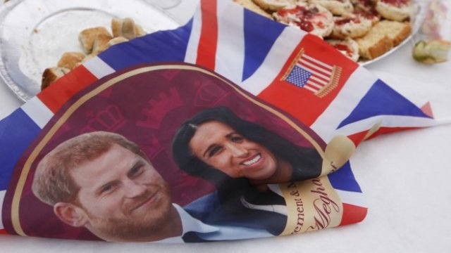 <p>
	Знаме с изображение на принц Хари и Меган Маркъл по време на улично парти, с което бе отпразнувана сватбата на британския принц Хари с Меган Маркъл, на 19 май 2018 г. <em>Фотограф: Лука Макгрегър / Bloomberg</em></p>
