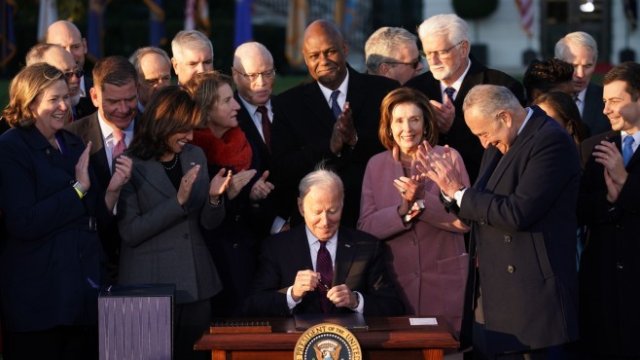 <p>
	Президентът на САЩ Джо Байдън, в центъра, подписва HR 3684, Закона за инфраструктурни инвестиции и работни места, по време на церемония на южната морава на Белия дом във Вашингтон, в понеделник, 15 ноември 2021 г. &nbsp;<em>Снимка: Stefani Reynolds/Bloomberg&nbsp;</em></p>
