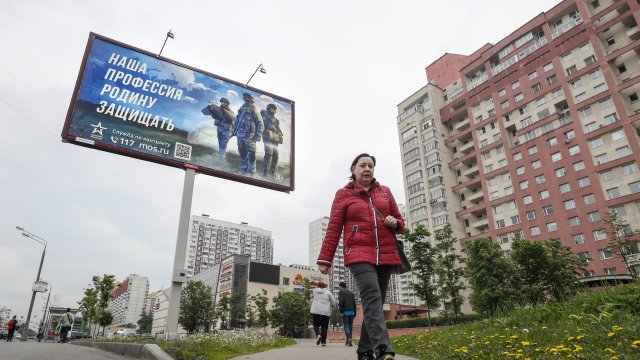 Жена минава покрай рекламиращ мобилизацията билборд в Москва. Снимка:  EPA/YURI KOCHETKOV