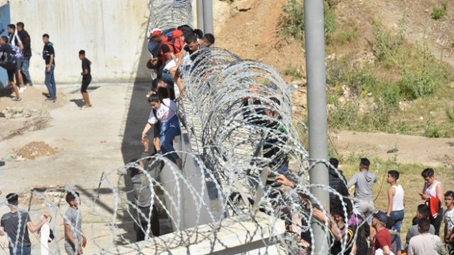 <p>
	<em>Мигранти прескачат оградата в северния марокански град Фнидек в опит да прекосят границата от Мароко до испанския анклав Сеута в Северна Африка.</em> <em>Снимка: EPA/JALAL MORCHIDI&nbsp;</em></p>
