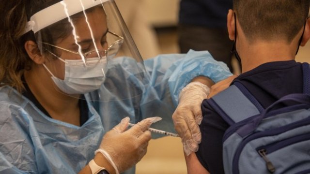 <p>
	<em>Здравен работник прилага ваксина срещу Covid-19 на ученик в мобилна ваксинационна клиника в гимназия в Лос Анджелис, САЩ. Снимка:&nbsp;Jill Connelly/Bloomberg</em></p>
