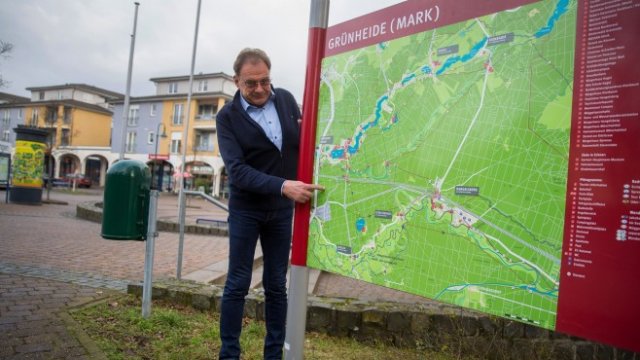 <p>
	Арне Кристиани, кмет на Грюнхайде, позира за снимка до карта в града. <em>Снимка: Кристиан Бочи / Блумбърг</em><br />
	&nbsp;</p>
