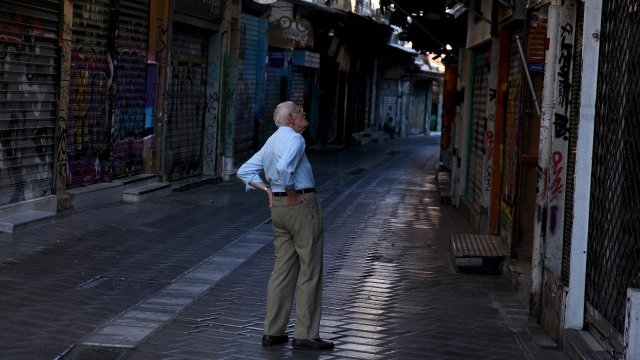 <p>
	Пенсионер се разхожда пред затворени магазини в центъра на Атина. <em>Снимка: Ройтерс</em></p>
