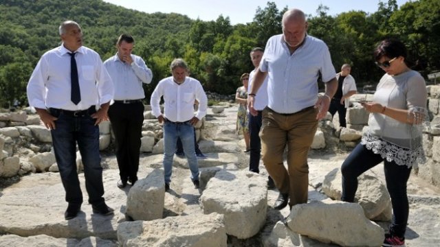 <p>
	Премиерът Бойко Борисов (ляво), заедно с министъра на културата Боил Банов (трети отляво) се запозна с последните открития при разкопките на Перперикон. Те бяха представени от ръководителя на обекта проф. Николай Овчаров (втори отдясно). Сред присъстващите бе и председателят на НС Цвета Караянчева (дясно). <em>Снимка: БТА</em></p>
