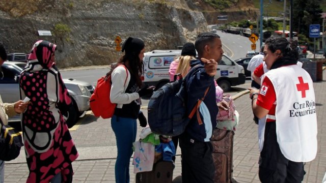 <p>
	Мигранти от Венецуела молят за помощ член на Червения кръст на границата с Еквадор. <em>Снимка: Ройтерс</em></p>
