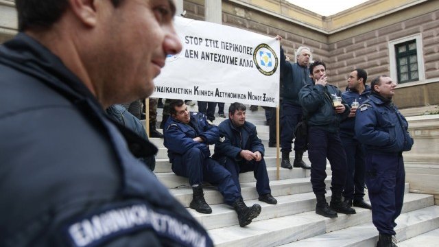 <p>
	Малка група служители на реда протестира вчера пред парламента в Атина. Икономическите мерки предвиждат орязване на заплатите на полицаи и пожарникари.<em> Снимка: Ройтерс</em></p>
