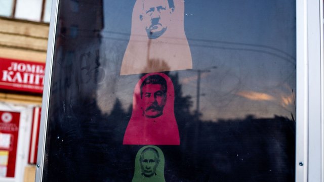 Уличен плакат с матрьошки с образите на Адолф Хитлер (отгоре), Йосиф Сталин (в средата) и и президента на Русия Владимир Путин (отдолу) в Запорожие, Украйна. Снимка: Julia Kochetova/Bloomberg