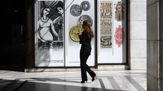 <p>
	Жена наблюдава един от клоновете на Алфа банк в Атина. Снимка: Ройтерс</p>
