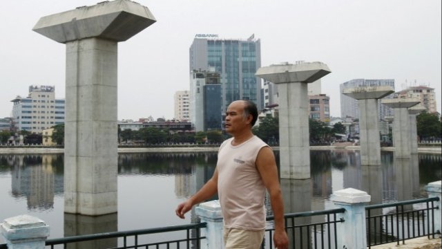 <p>
	Мъж преминава край недовършени стълбове от градската жп линия в Ханой.&nbsp;<em>Снимка: Архив Ройтерс</em></p>
