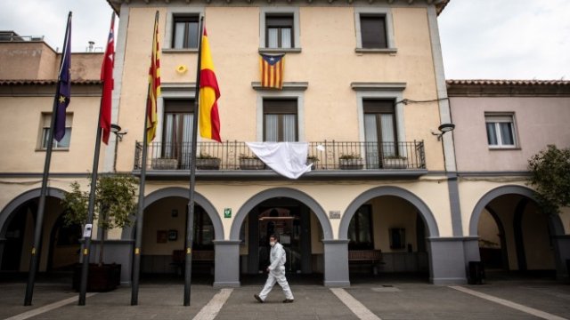 <div class="photo-info">
	Хуан Кабрера, местен общински работник, минава покрай кметството, докато доставя комплекти от маски за лице на местните жители като част от доброволческа акция в град Сентменат, Испания. Снимка: <em>Angel Garcia / Bloomberg </em></div>
