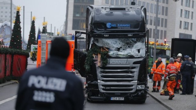 <p>
	Полицай стои пред камиона, който снощи се вряза в пълен с хора коледен базар в Берлин. <em>Снимка: Ройтерс</em></p>
