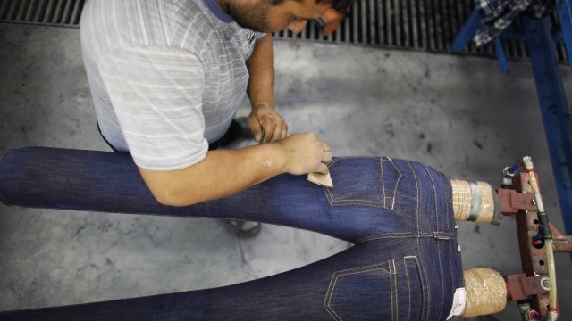 <p>
	Работник във фабриката на гръцката компания Staff Jeans and Co в Раковски. <em>Снимка: Ройтерс</em></p>
