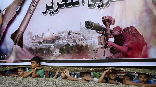 <p>
	Палестинци се крият зад огромен постер на Хамас в град Рафах в ивицата Газа. <em>Снимка: Ройтерс</em></p>
