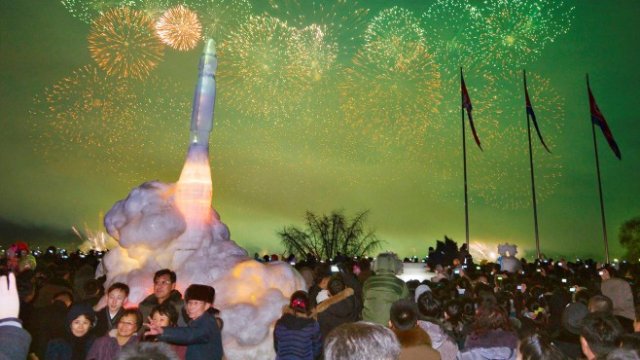 <p>
	<em>Фойерверки отбелязват идването на Нова година на площада в Пхенян, докато граждани се снимат на фона на ледена скулптура на междуконтинентална балистична ракета. Снимка: Ройтерс</em></p>
