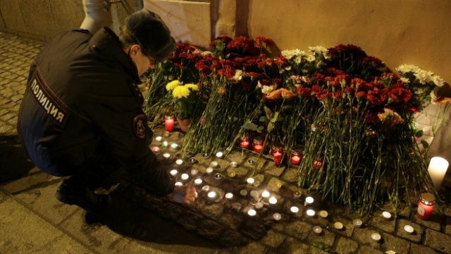 <p>
	Полицай поднася цветя в памет на жертвите. <em>Снимка: Ройтерс</em></p>
