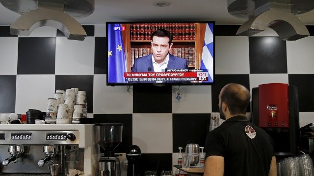 <p>
	Сервитьор в кафене в Атина проследява на живо изявлението на премиера. <em>Снимка: Ройтерс</em></p>
