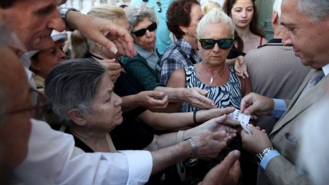 <p>
	Банков служител в Атина раздава номера на пенсионери, които чакат да си получат пенсиите. <em>Снимка: Ройтерс</em></p>
