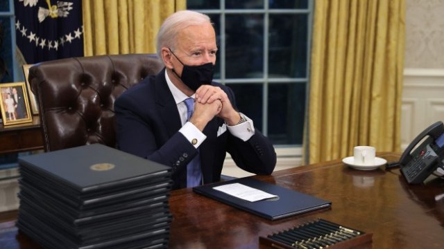 <p>
	Байдън подписва първите документи като президент. Снимка: Bloomberg LP</p>
