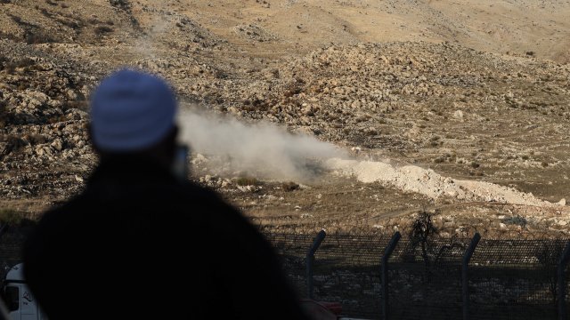 Мъж наблюдава контролирана експлозия в буферната зона между Израел и Сирия. Снимка: EPA/ATEF SAFADI 