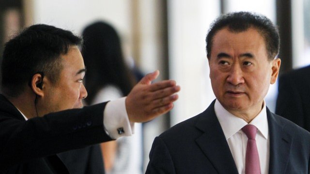 <p>
	Мъж показва пътя на изпълнителния директор на Dalian Wanda Уан Дзиенлин. <em>Снимка: Ройтерс</em></p>
