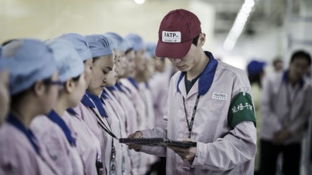 <p>
	Супервайзор проверява баджовете на служители в завод на Pegatron в Шанхай. <em>Снимка: Qilai Shen/Bloomberg</em></p>
