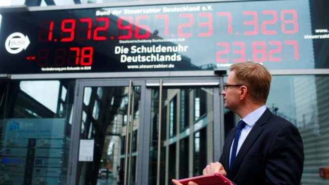 <p>
	Райнер Холцнагел стои пред препрограмирания &quot;часовник на дълга&quot;. <em>Снимка: Ройтерс</em></p>
