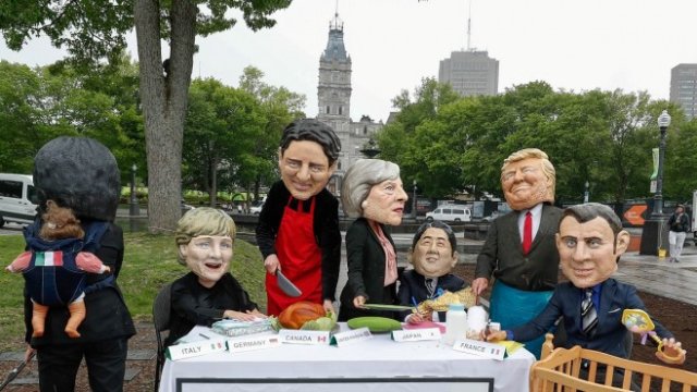 <p>
	Протестиращи активисти, носещи маски на лидерите на Г7. <em>Снимка: Архив Ройтерс</em></p>
